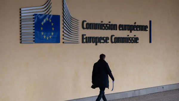 A person walks under a sign on a wall that reads Commission européenne