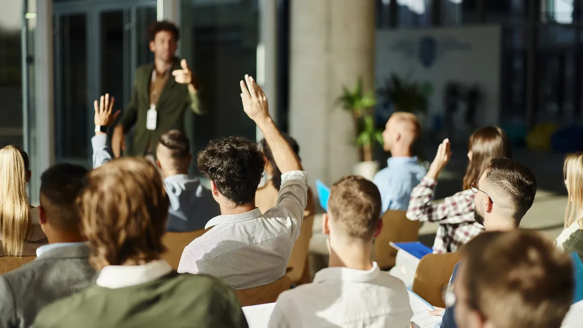 Back view of entrepreneurs raising hands on a seminar in board room. - stock photo