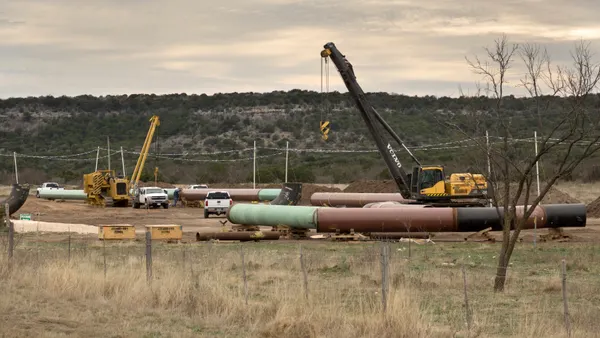 Pieces of pipeline sit next to heavy equipment.