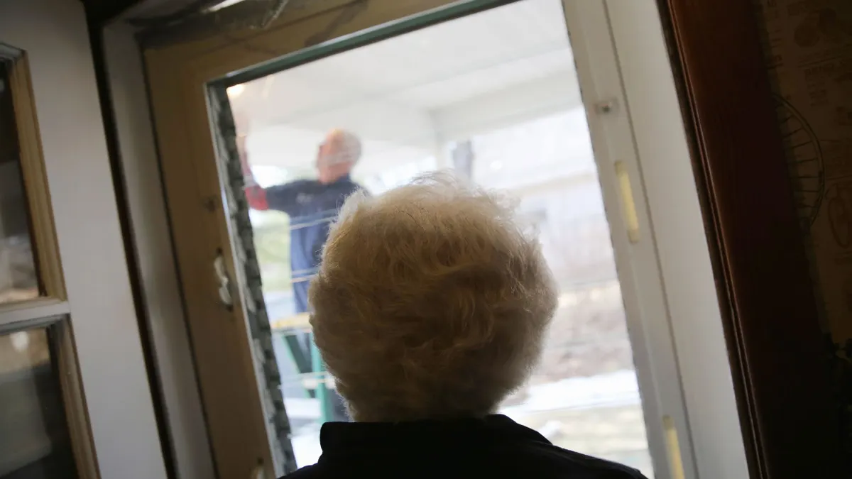 A technician replaces a light bulb outside a senior's home.