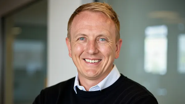 A person smiles while wearing a black sweater.