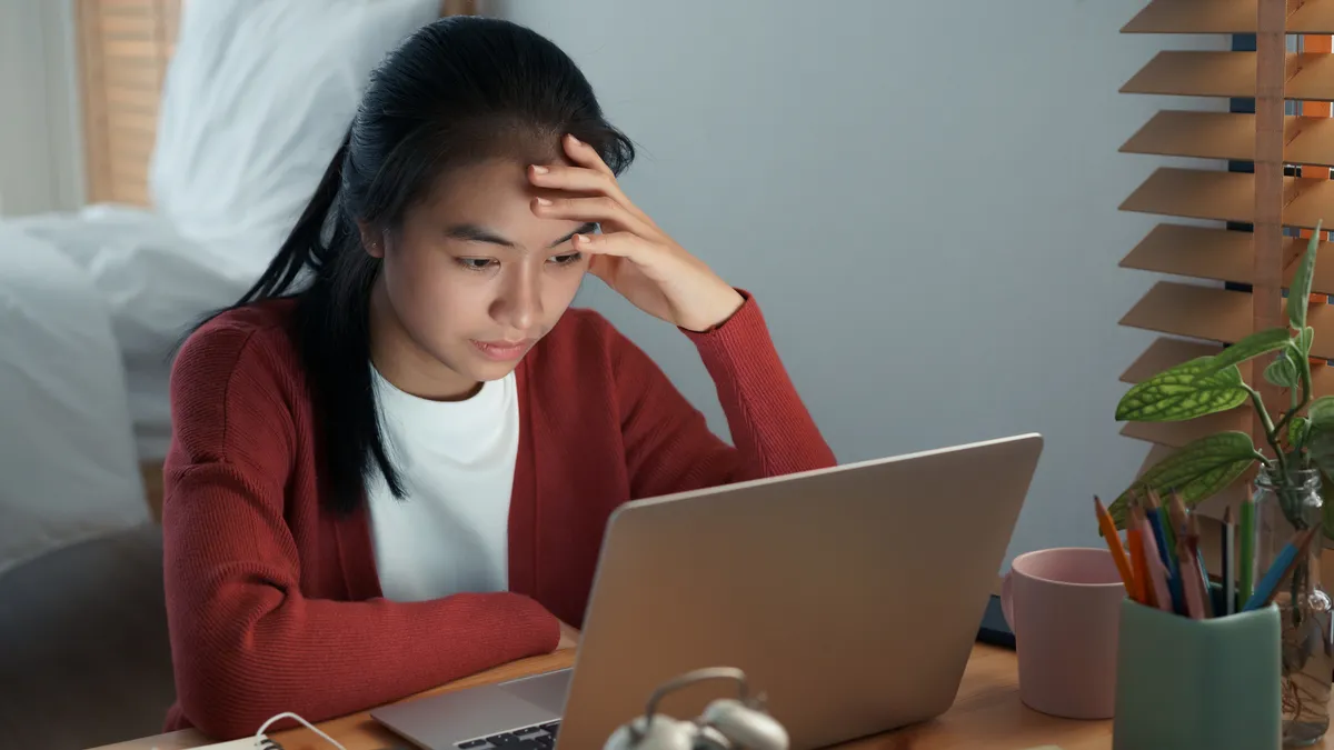 A student sits at a desk with head in hands