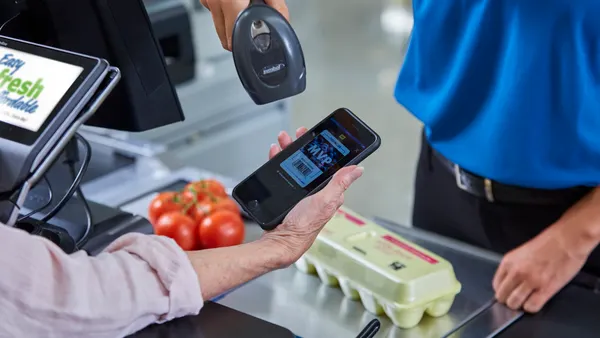 A grocery shopper getting their loyalty program barcode scanned at checkout.