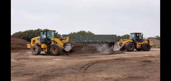 Two tractors scooping compost