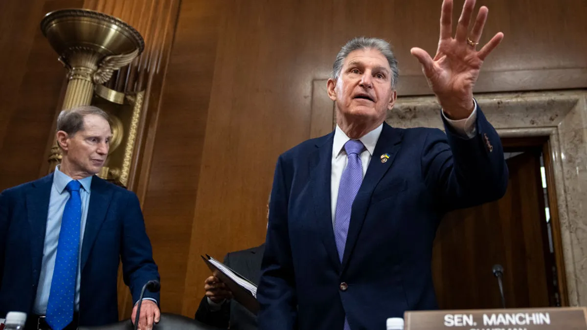 Sen. Joe Manchin speaks at a meeting with his left hand raised