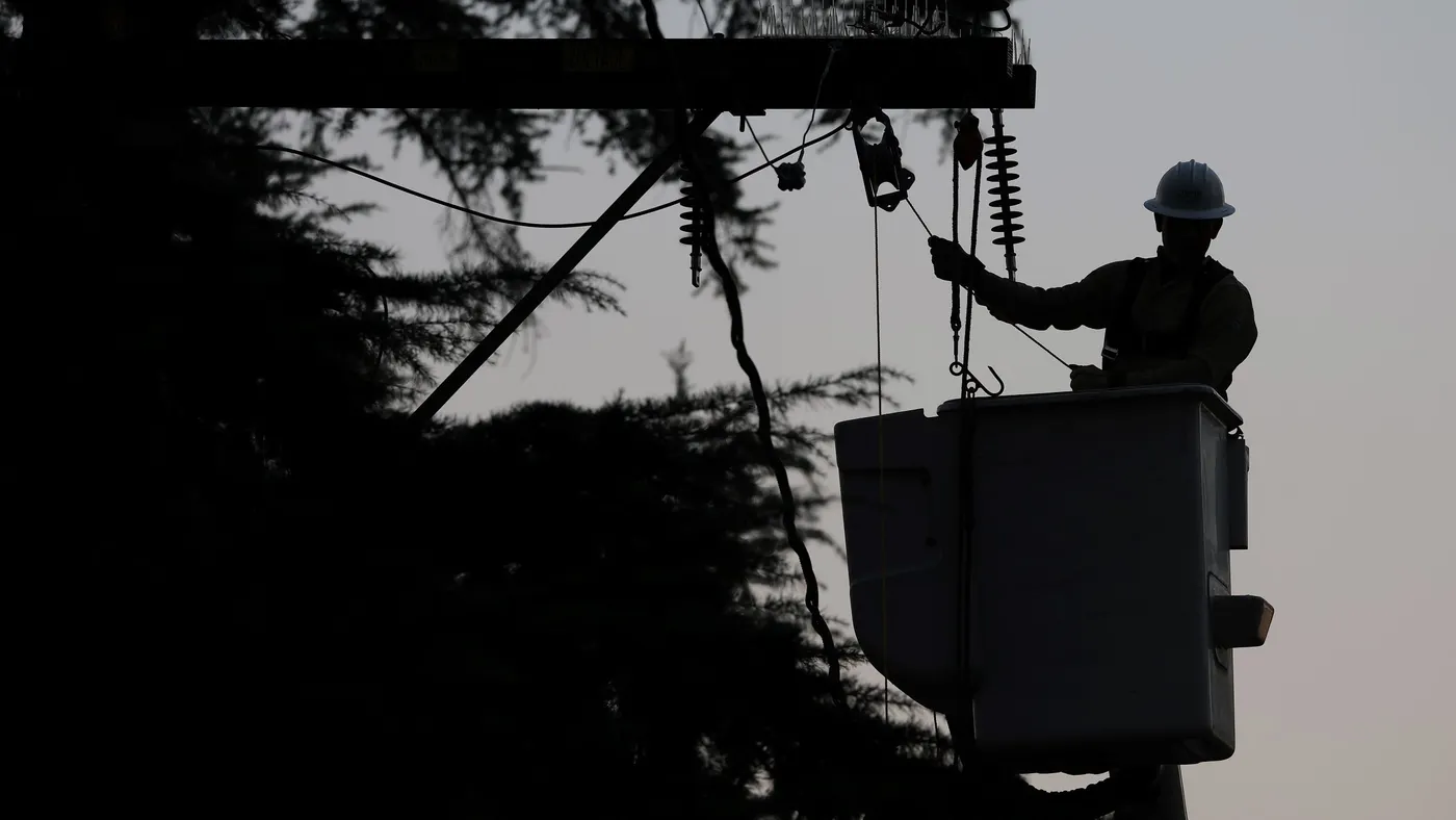 A utility worker makes repairs to electrical lines