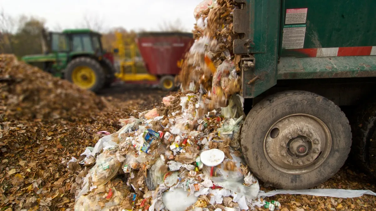 A sall vehicle dumps mixed waste onto an organics pile.