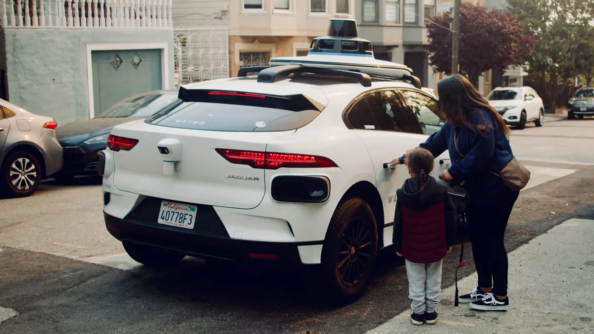 Two people prepare to enter a Waymo ride-haling vehicle in San Francisco.