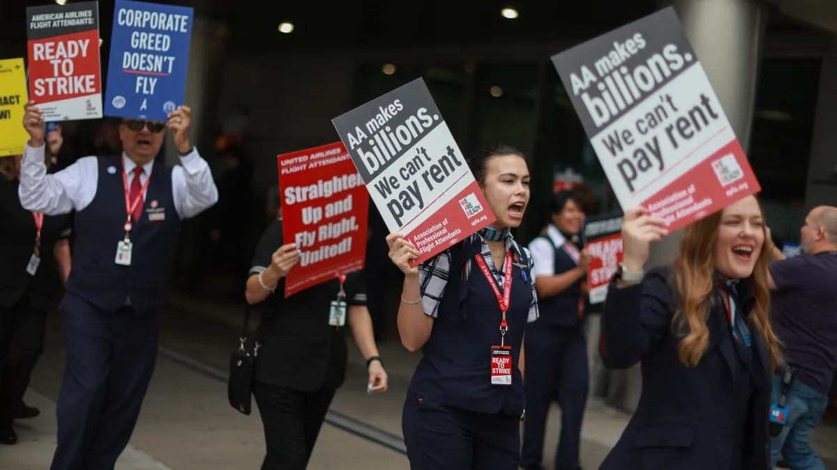 Individuals wearing airline uniforms carry signs saying they can't pay rent.