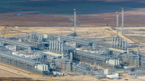 A sky-high view of a large collection of silver pipes in an arid region.