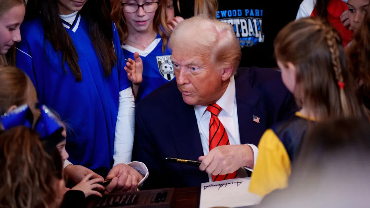 Trump hands out pens to girls after signing his executive order.