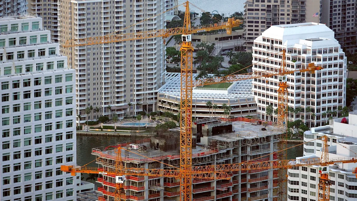 Apartment building under construction surrounded by high rises.