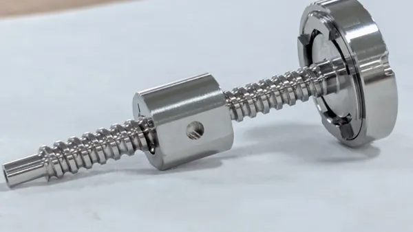 A silver screw laid on a white table.