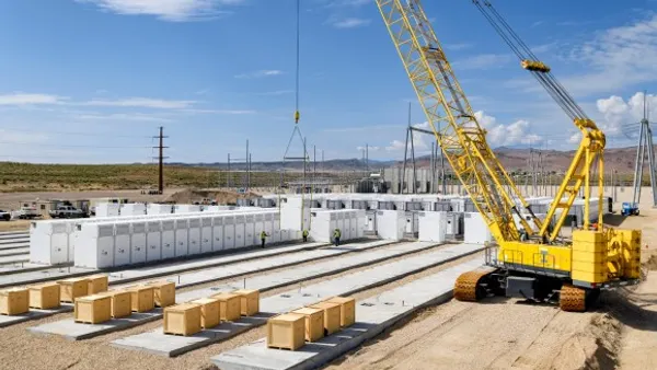 A crane lowers a battery storage container onto a concrete pad.