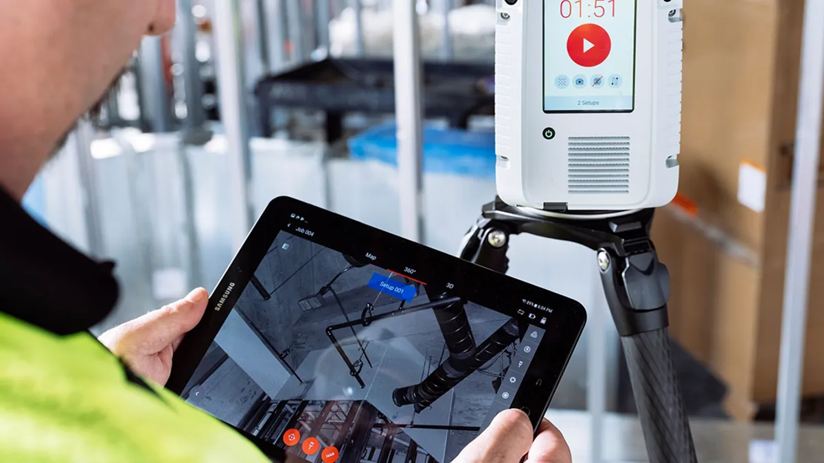 A construction worker with an iPad and a Leica RTC360.