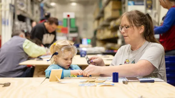 A mother and her child work on a DIY project inside a Lowe's store.