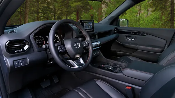 The driver side of a 2023 Honda Pilot SUV showing the steering wheel and dashboard.