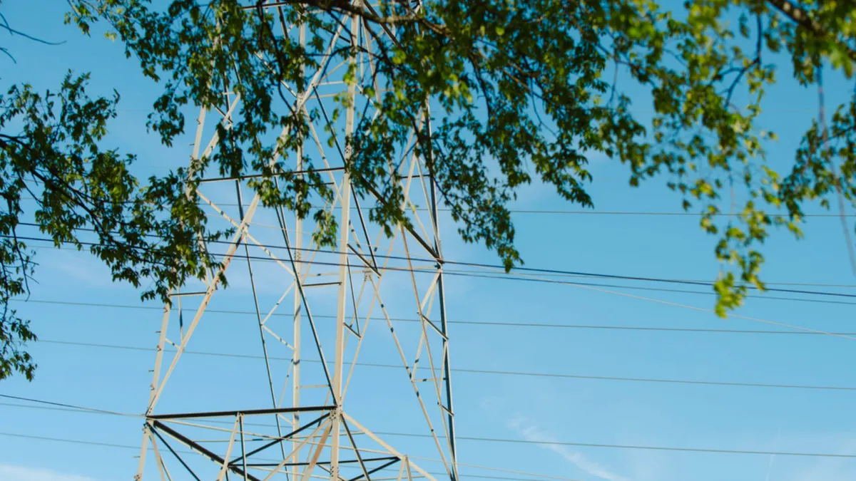 Steel lattice transmission tower with power lines against clear sky.