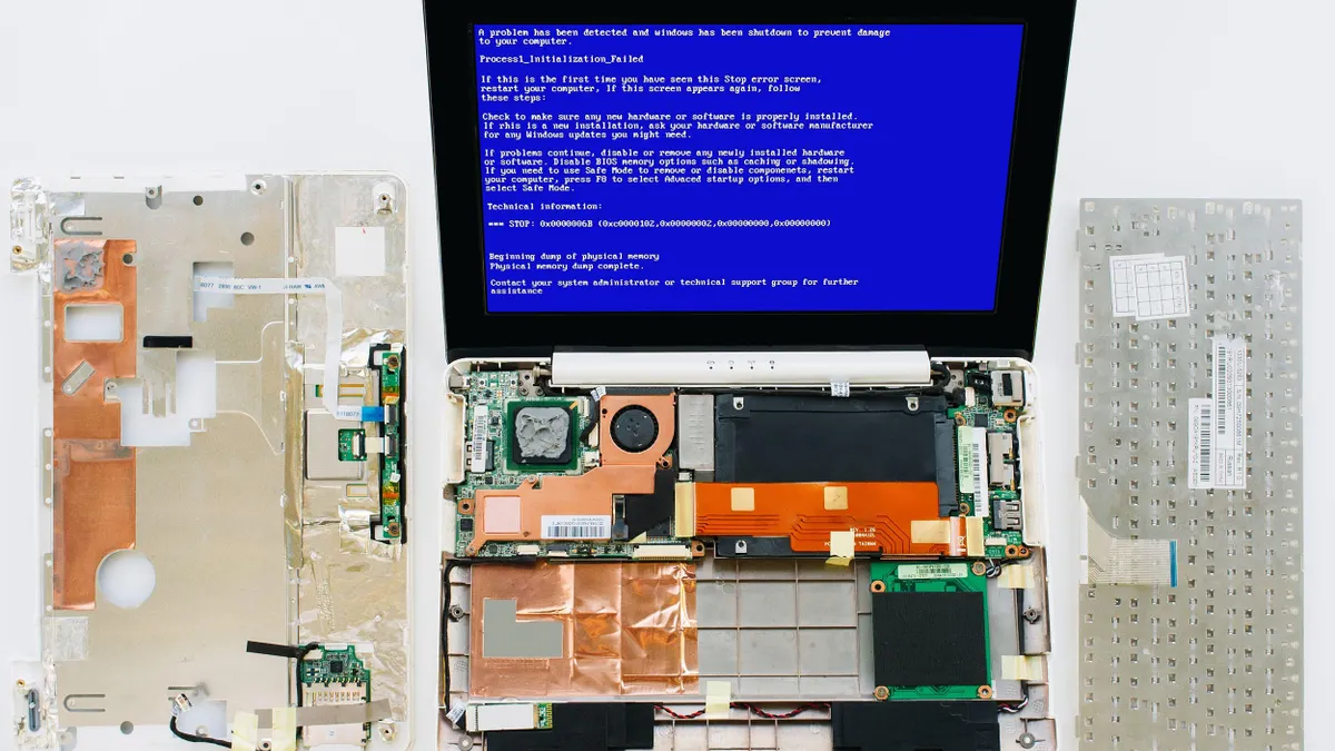 A dissembled computer is displayed across a white surface; the monitor is blue with white text stating, "There is a problem with your computer.."