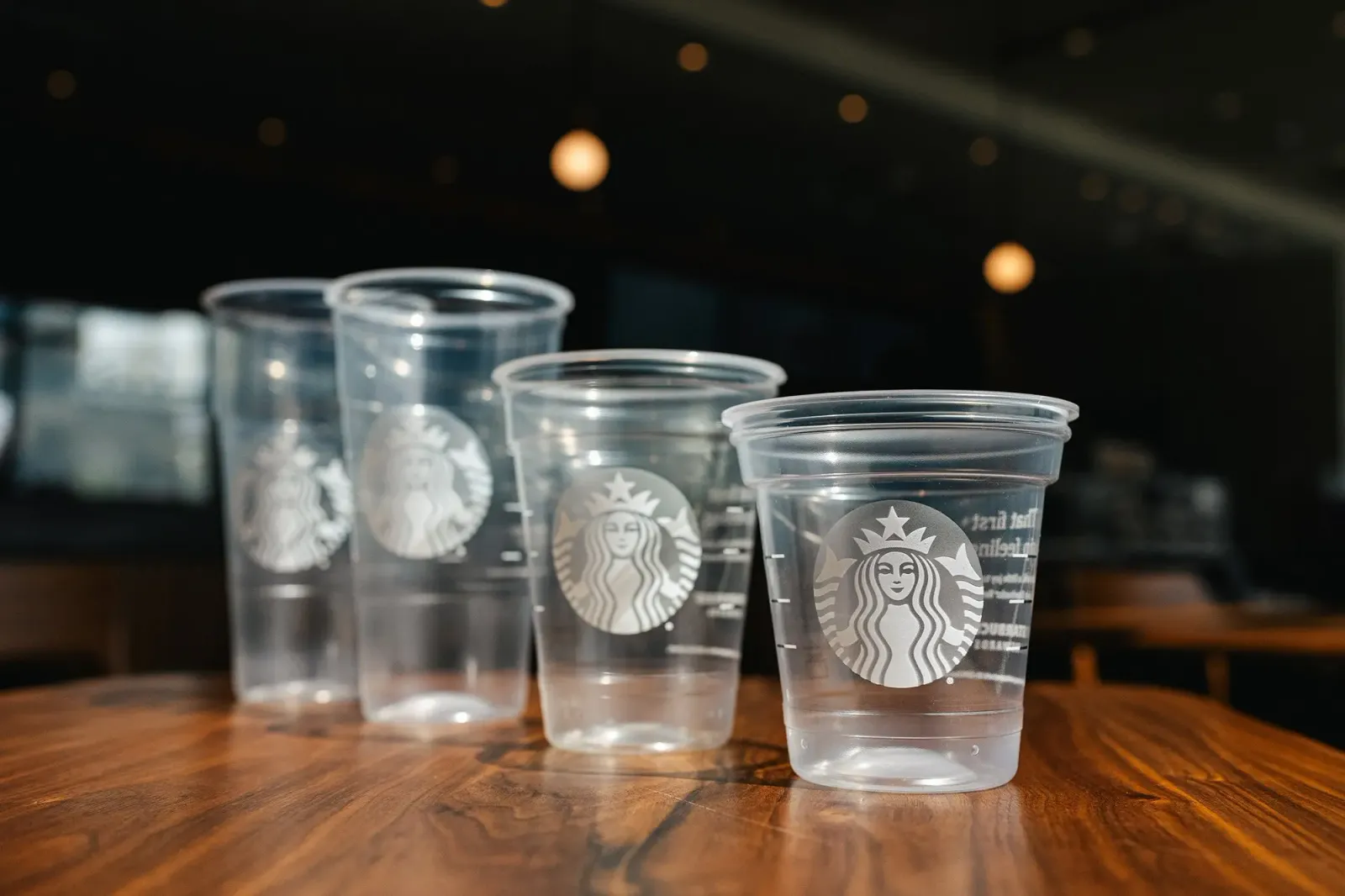 Four different sizes of plastic cups with Starbucks&#x27; branding on the side.