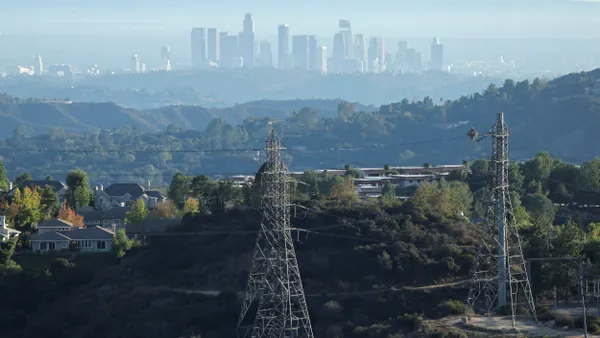 Electrical transmission towers stand with a city in the distance