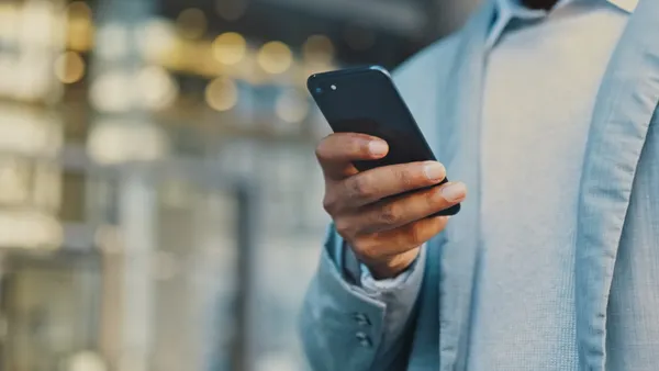 A man holds a black cell phone.
