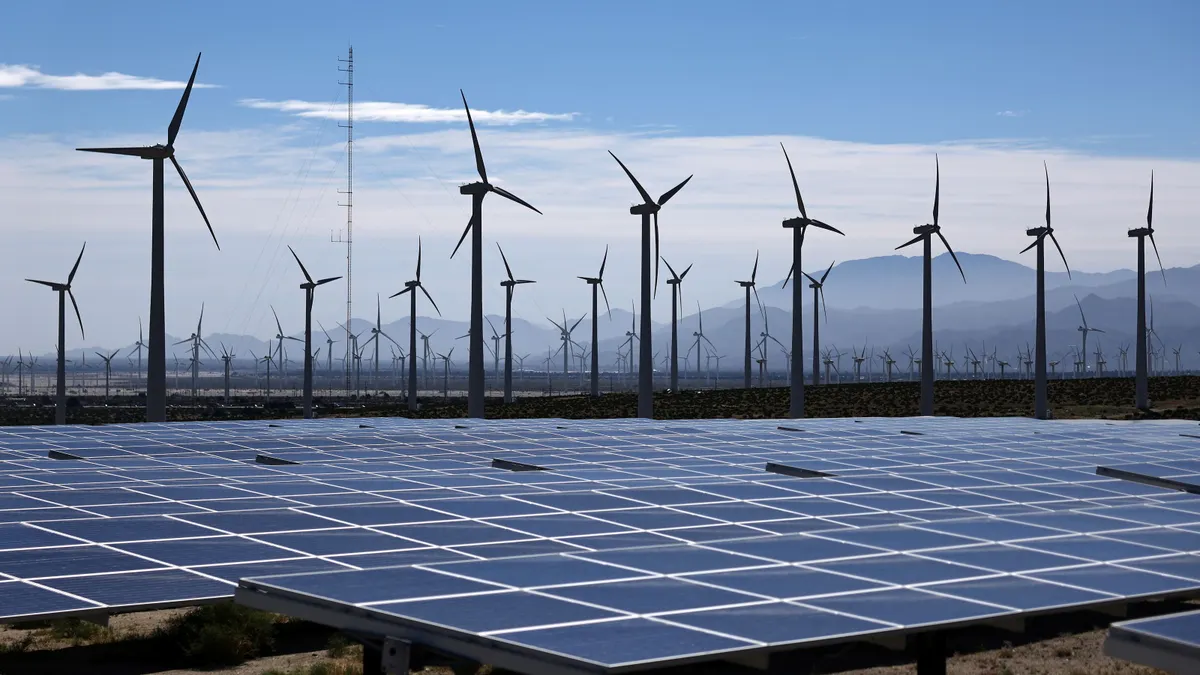 Solar panels and wind turbines in a desert landscape.