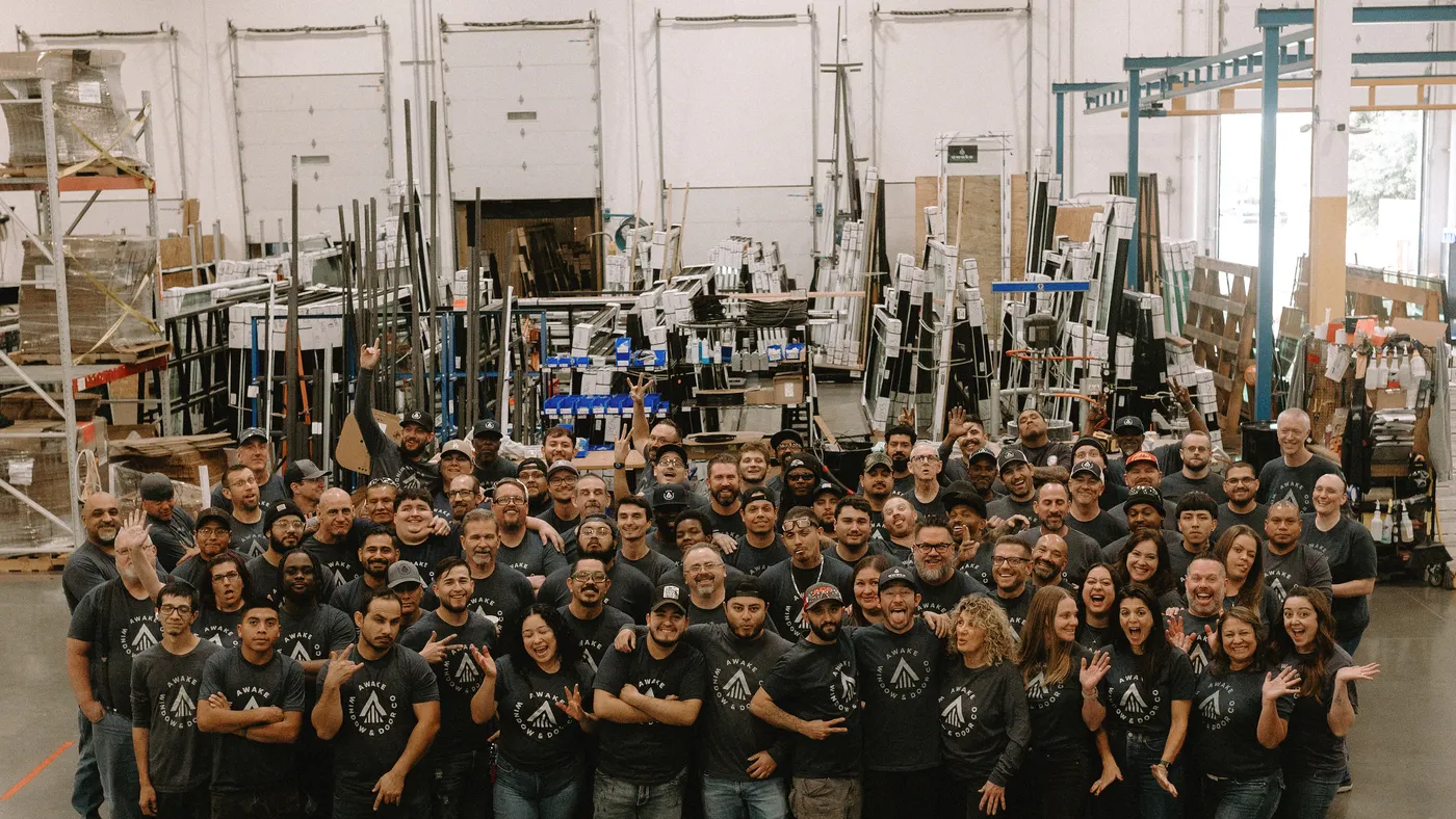 A large group of people in Awake Window & Door's manufacturing facility