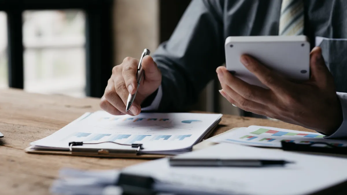 Businessman using a calculator to calculate numbers on a company's financial documents