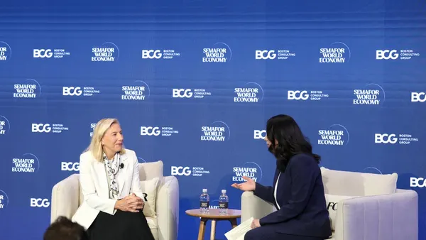 Tapestry CEO Semafor in white suit sitting on a blue stage