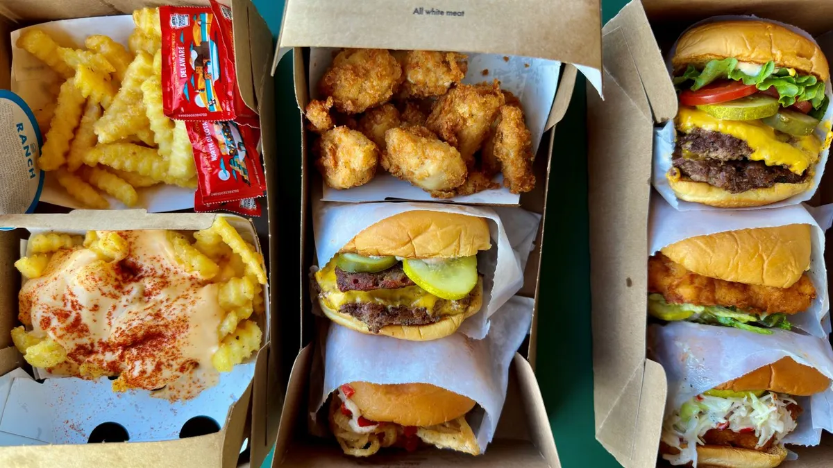 A photograph of various burgers, chicken sandwich, chicken nuggets and fries in cardboard packaging.
