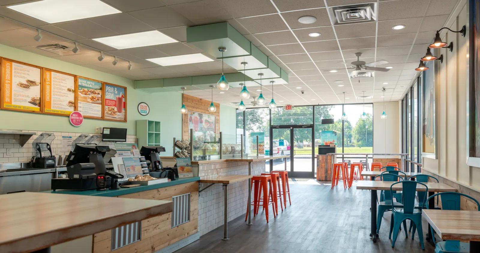Inside a restaurant with tables, chairs and a front counter.