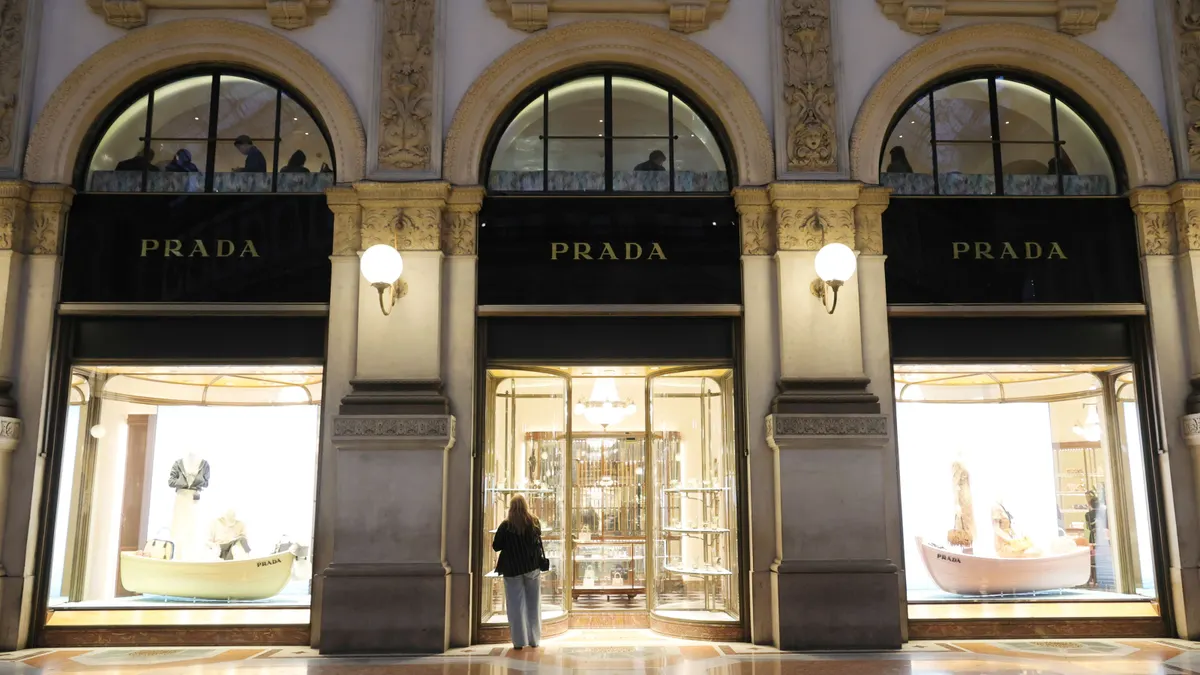 A golden Prada storefront is lit up at night.