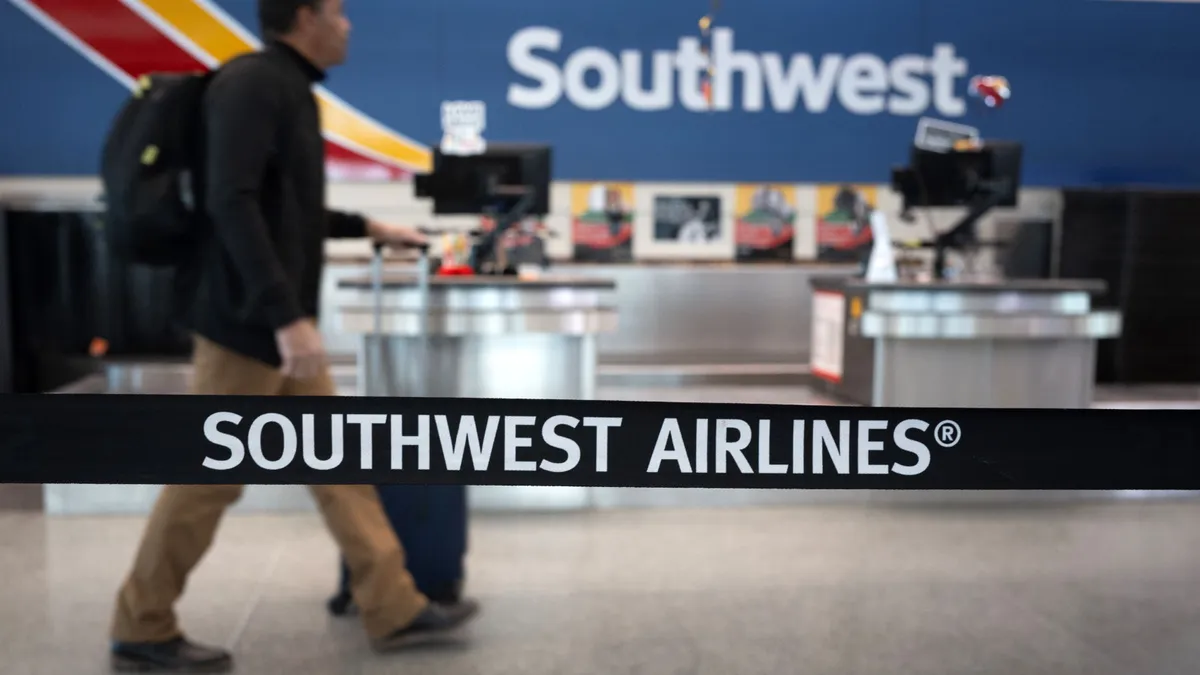 A traveler walks by check-in at Southwest with a bag.