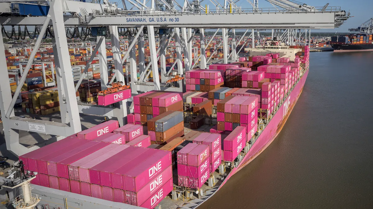 An ocean vessel filled with containers docks at a water port.