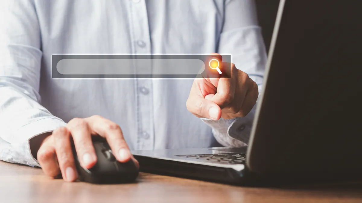 A businessperson uses a laptop to search for information on a web browser