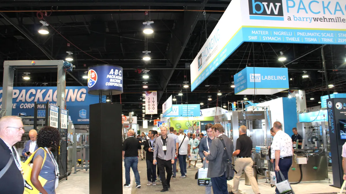 Attendees walk among vendor booths in an exhibition hall at Pack Expo in Las Vegas.