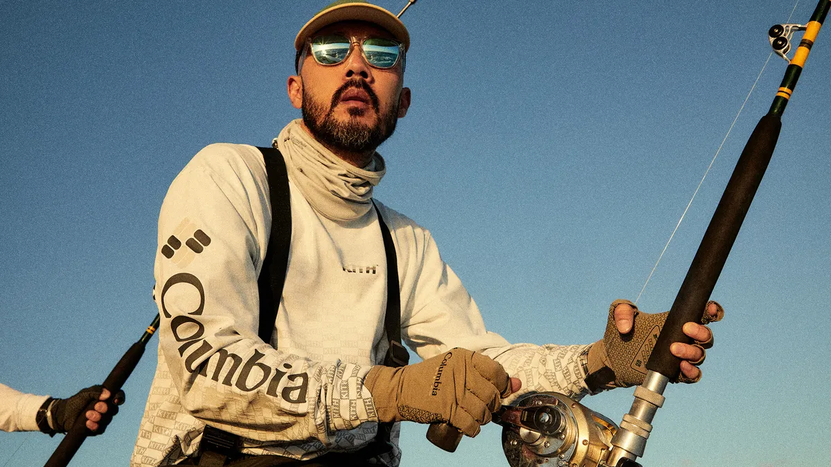 A person is fishing and wearing cream colored fishing gear and sunglasses.