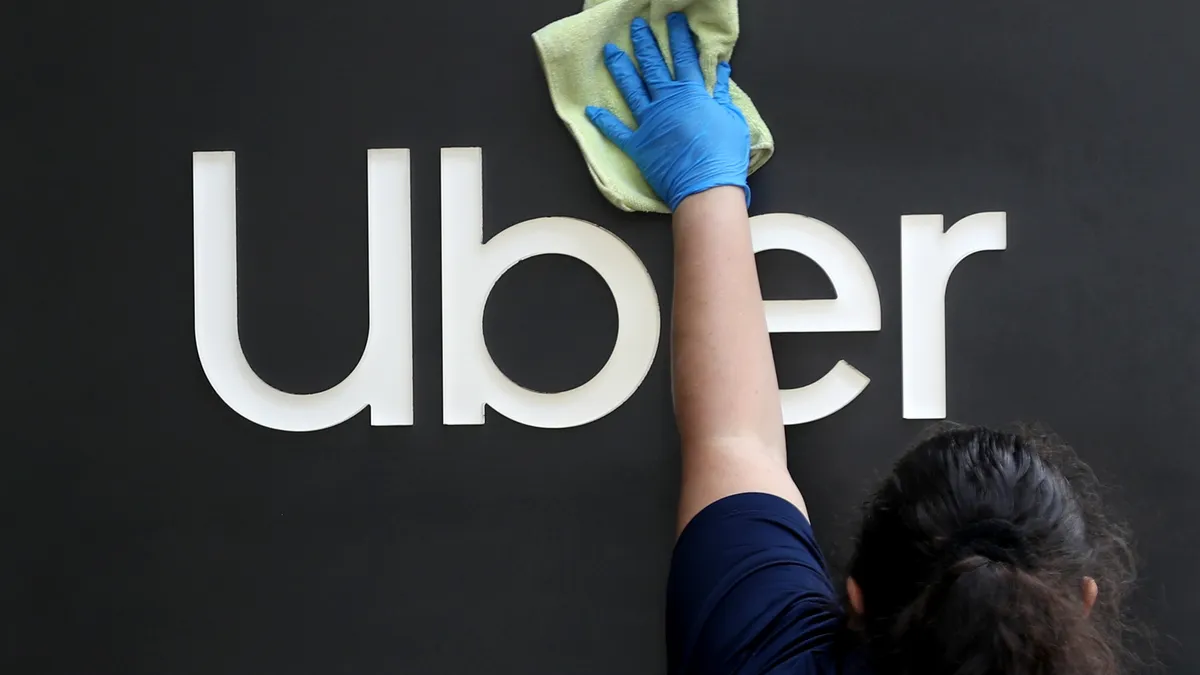 A worker cleans a sign in front of the Uber headquarters on May 18, 2020 in San Francisco, California.