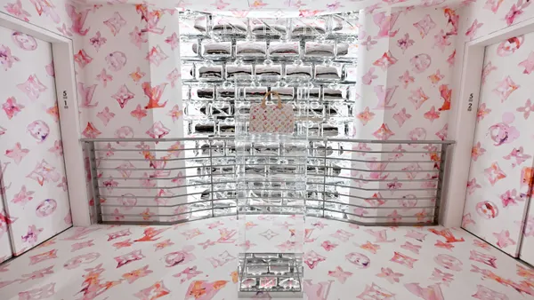 A handbag on display against a pinkish background featuring the logo of Louis Vuitton.
