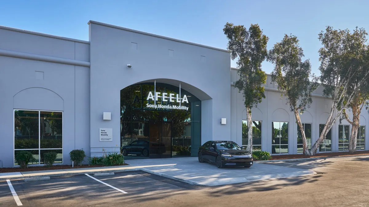 A building sign says "AFEELA" with the words "Sony Honda Mobility" below it, and a sedan parked in front.