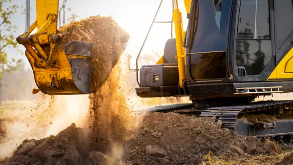 A mechanical digger lifts dirt at a construction jobsite.
