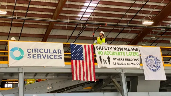 A worker stands near a Circular Materials sign at a MRF