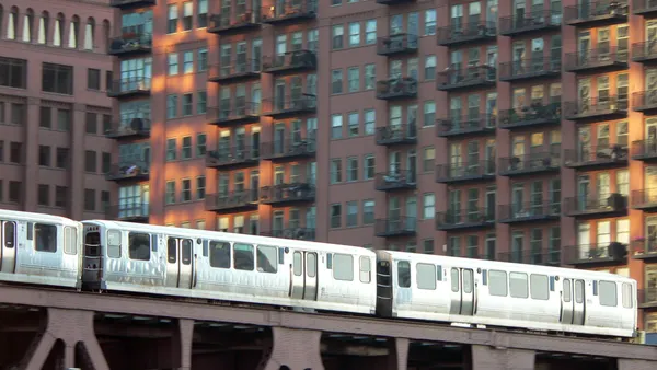 A train on a bridge in front of brick apartment buildings.