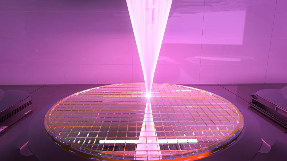 A bright beam of light etching a large round wafer, color-graded in orchid.