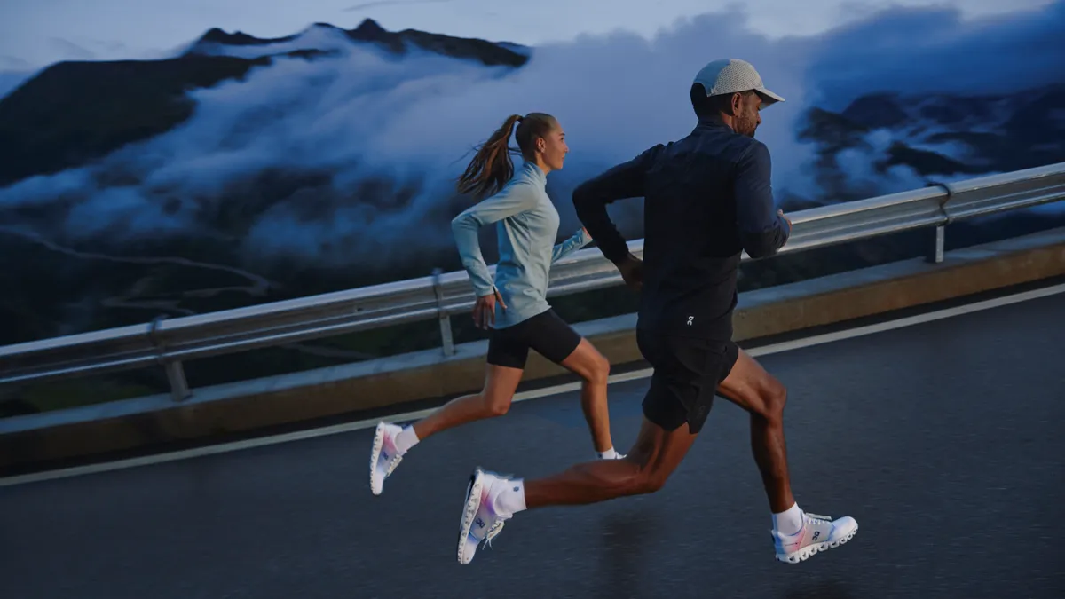 Two runners in long sleeves on a road with clouds in the sky