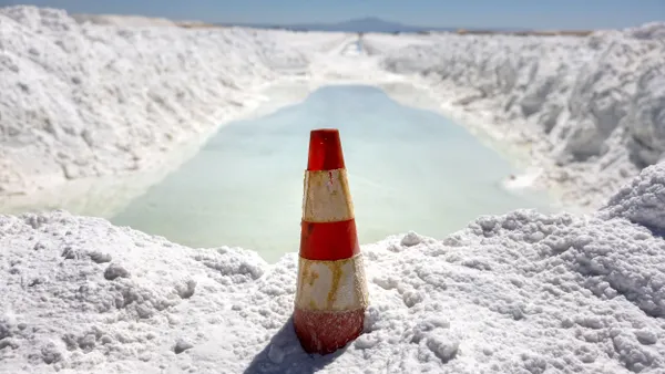 Lithium-rich brine dries in an evaporation pond next to mounds of salt bi-product at a lithium mine