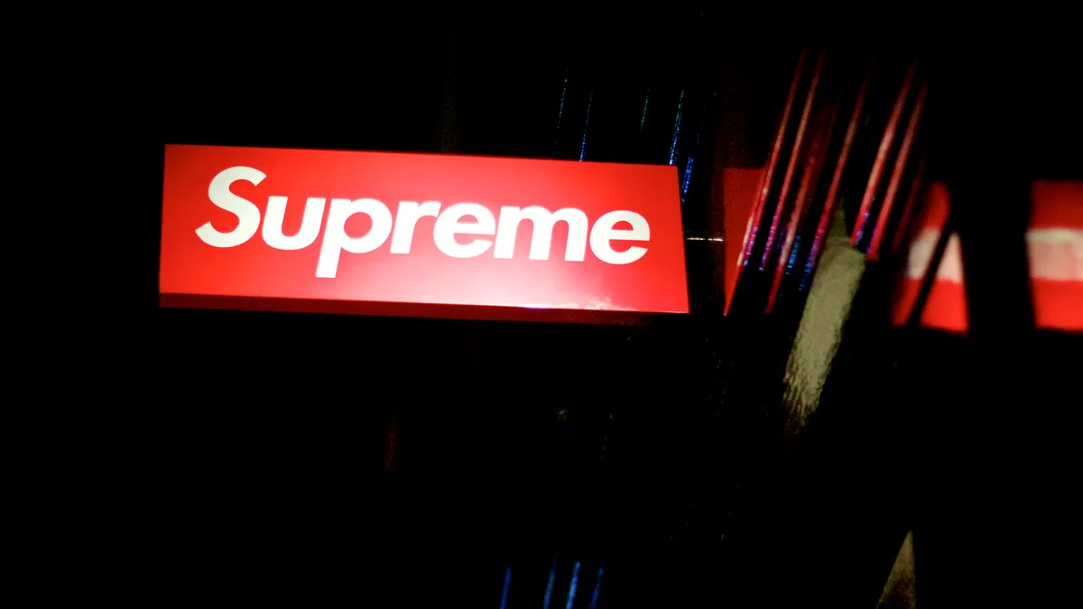 A red sign with the Supreme logo is pictured illuminated at night.