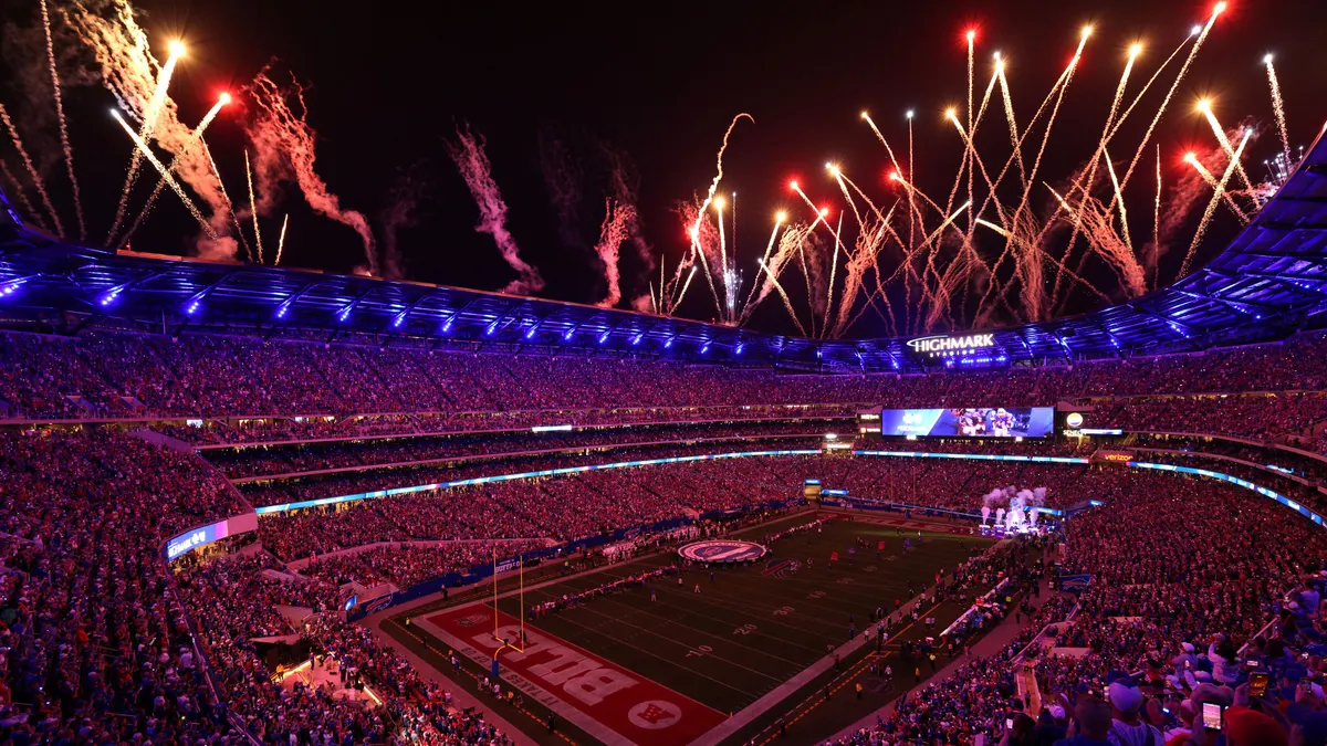 Fireworks explode over a stadium bowl at night time.