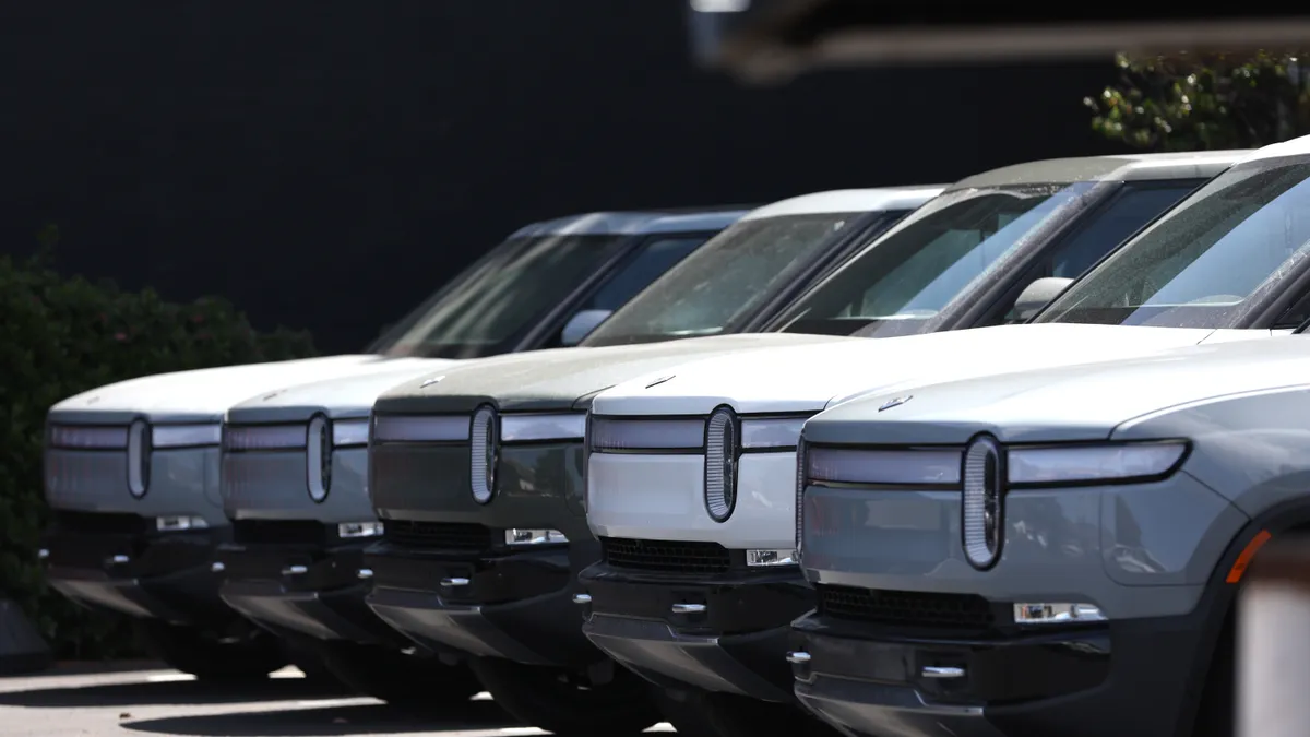 Rivian electric pickup trucks are parked in a line.